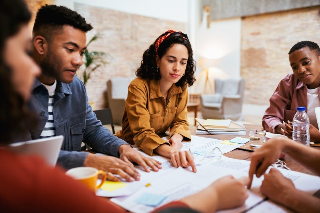 A team of 5 reviewing documents in a co-design team meeting