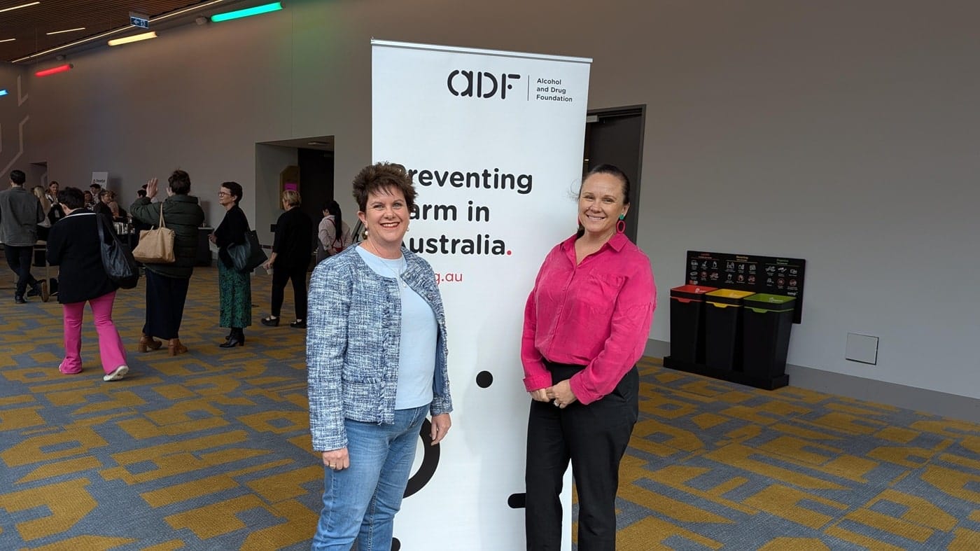 Two female clinicians posing at ADF event banner, showcasing partnership and user-centered health design.