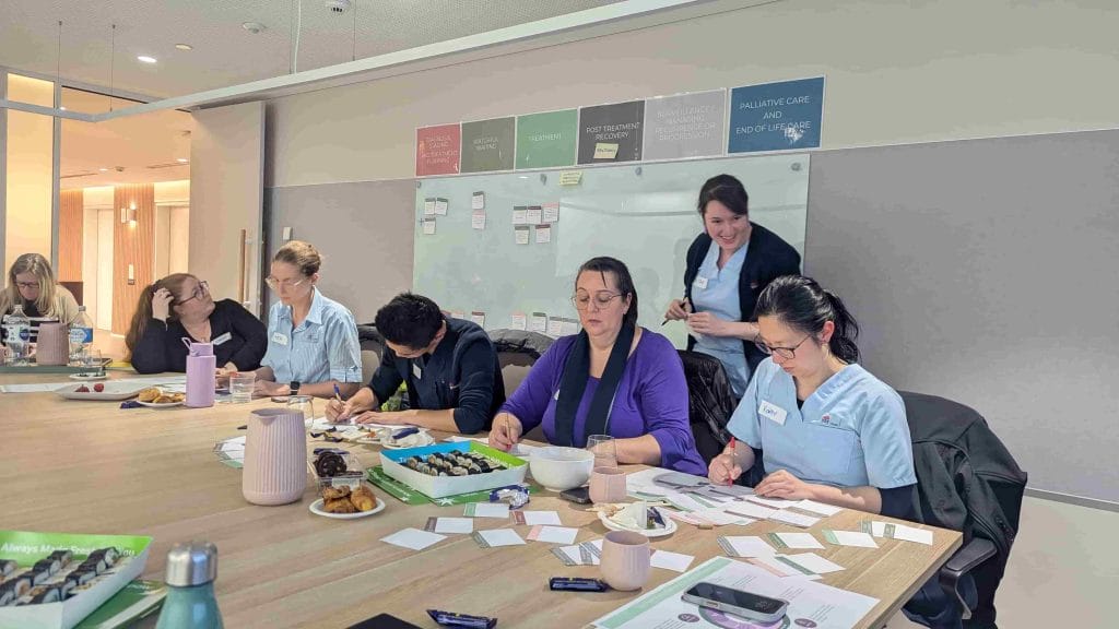 People working in boardroom with facilitator assisting, showcasing co-design, guided collaboration, and inclusive decision-making.